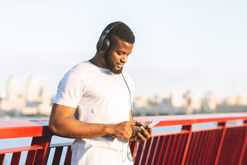 Afro jogger setting playlist on cellphone before exercising
