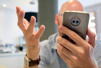 Man gesturing vividly while handling smartphone