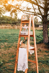 Fototapeta na wymiar Rustic wedding photo zone. Hand made wedding decorations includes Photo Booth, wooden barrels and boxes, lanterns, suitcases and white flowers