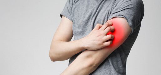 Man scratching his red itching hand, panorama