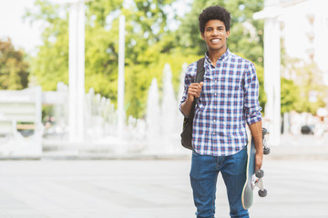 Handsome male teenager with skateboard posing to camera