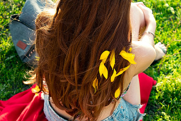 Girl with gorgeous wavy hair with sunflower petals.  Girl on a picnic around the green grass.