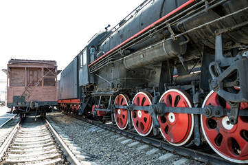 Black steam locomotive and an old wooden wagon.