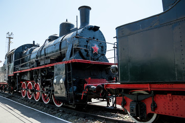 Black Soviet locomotive with a red star is on the rails.