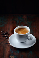Cup of coffee and coffee beans on rustic wooden background. Copy space.