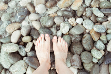 Human feet on various colored stones, top view image showing variety of minerals in many shapes and colors