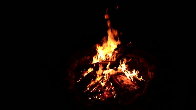 Static timelapse of yellow flames lapping around a bonfire at night