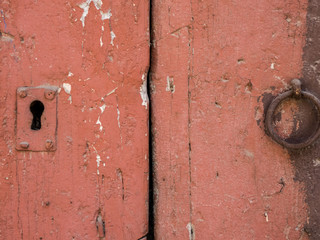 Rusty iron ring door knob and keyhole over an old wooden grunge door