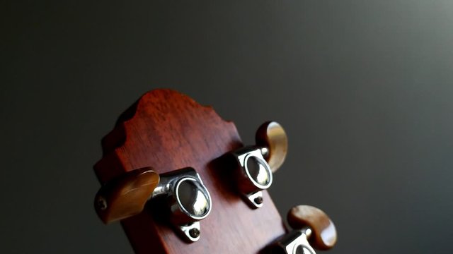 Close-up tilt down shot of tuning pegs in acoustic guitar.