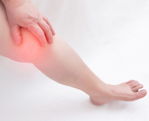 The leg of an elderly woman on a white background in which there is pain in the knee. Knee diseases arthrosis and arthritis in the elderly, copy space