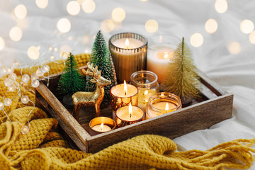 Wooden tray with burning candles  and christmas decorations on with warm plaid. Winter cozy style....