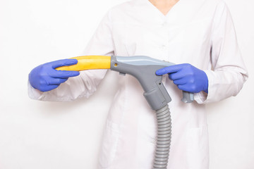 Doctor holding a banana near the vacuum cleaner on a white background, concept of increasing member in men with a vacuum pump