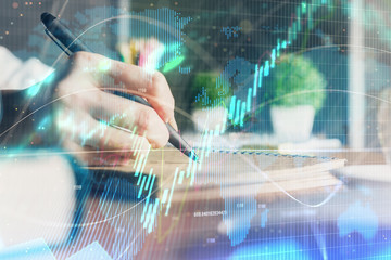 Financial forex charts displayed on woman's hand taking notes background. Concept of research. Double exposure