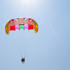 A couple in love fly across the sky on a parachute behind a yacht. A family that loves risky entertainment. Sea holidays in southern countries