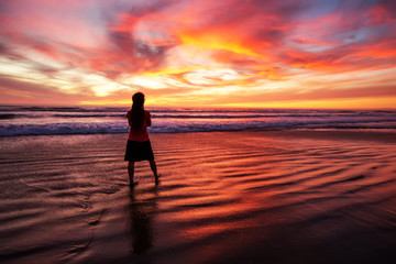 Fototapeta premium woman walking alone on the beach in the sunset