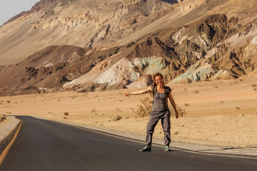 hitchhiker woman walking on a road in USA