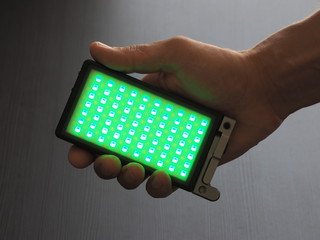 RGB light on a man hand, dark background. Green light.
