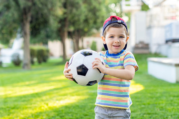Little boy play soccer at outdoor.Boy running towards ball on a field