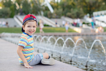 baby Boy sitting near the fountain in the city park