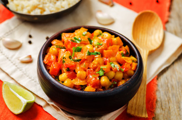 chickpeas carrots pepper coconut milk curry with brown rice on a wood background