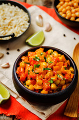 chickpeas carrots pepper coconut milk curry with brown rice on a wood background