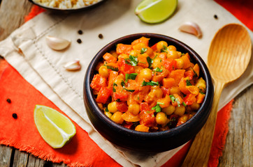 chickpeas carrots pepper coconut milk curry with brown rice on a wood background