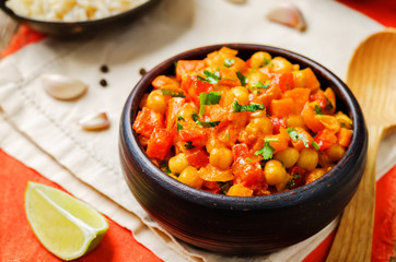 chickpeas carrots pepper coconut milk curry with brown rice on a wood background