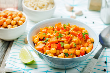 chickpeas carrots pepper coconut milk curry with brown rice on a wood background