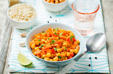 chickpeas carrots pepper coconut milk curry with brown rice on a wood background