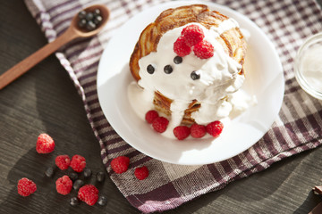 Top wiev of tasty pancakes on checkered cotton towel, muffins with sour cream, fresh blueberries and raspberries on white plate, spoon full of berries. Delicious pancackes for breakfast, food concept.