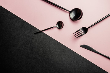 Elegant black and pink table setting: plates, napkin and silverware. Flat lay. Pink and black background
