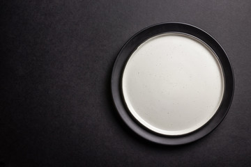 Elegant black table setting: plates, napkin and silverware over black background. Flat lay. copy space