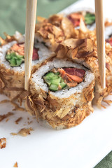 Sushi roll with chopsticks on a white plate close up.
