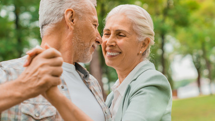 Close up shot of mature man and woman couple dancing at park and enjoying of each other
