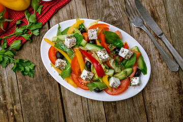 Greek salad with feta on wooden table