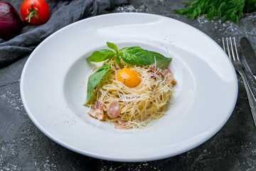 Spaghetti Carbonara with bacon and egg and basil on grey concrete background