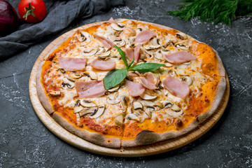 Pizza with ham and mushrooms on grey concrete background