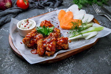 fried chicken wings in barbecue sauce on grey concrete background