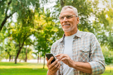 Low angle view of mature man standing outdoors using mobile phone