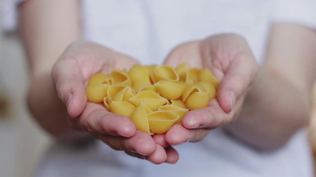 Woman’s hands holding pasta shells. Close up with a shallow depth of field