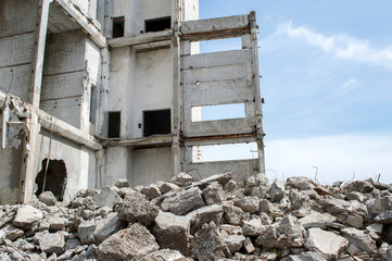 Concrete gray debris close-up on the background of the remains of the destroyed building against the sky. Background