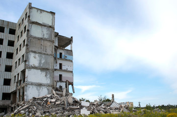 A pile of concrete debris with the remains of a large building against the blue sky. Background. Text space