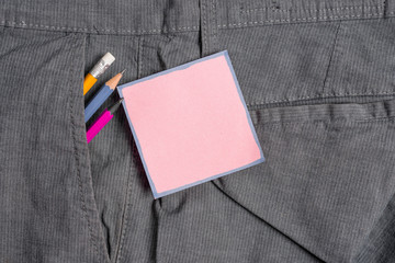 Writing equipment and pink note paper inside pocket of man work trousers