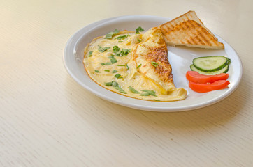 Omelet with cheese and parsley, sliced tomatoes and cucumbers on the plate. Scrambled eggs with copy space, top view. Healthy nutrition.