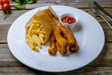 Chicken strips with ketchup and french fries on old wooden table