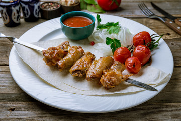 chicken wings on old wooden table with tomatoes and onion