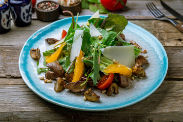 Salad with chicken liver on old wooden table