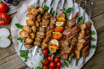 platter of different kebabs on old wooden table