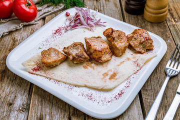 Kebab of veal on wooden table