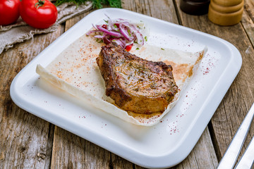 Fried pork loin with red onion on wooden table